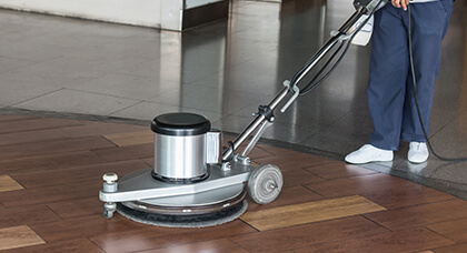Janitorial Floor Cleaning, Care, and Maintenance wood floor being polished by a janitor using a buffer machine